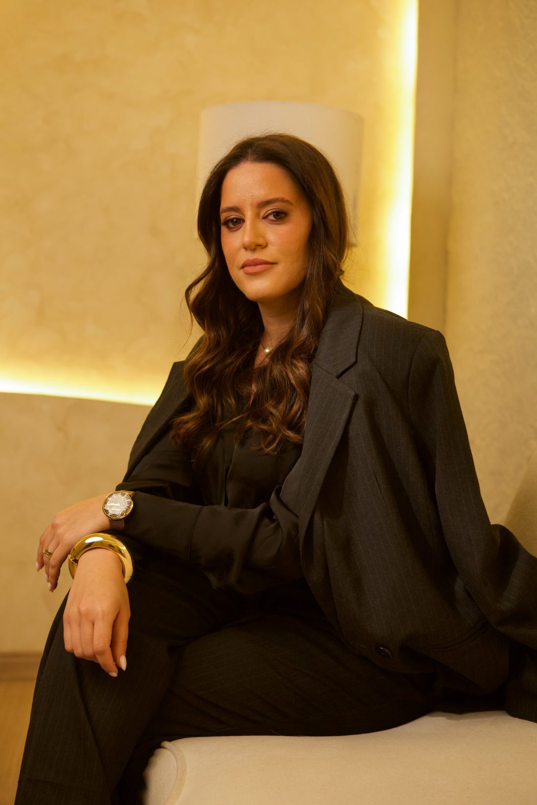 Alanna Chaves sentada em sofá claro, olhando para a câmera
